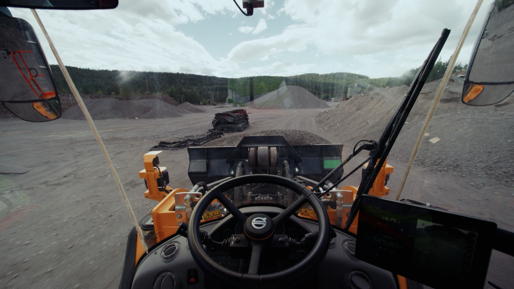 View from inside the cab of the Volvo wheel loader, looking across the quarry at Feiring Bruk over the raised bucket