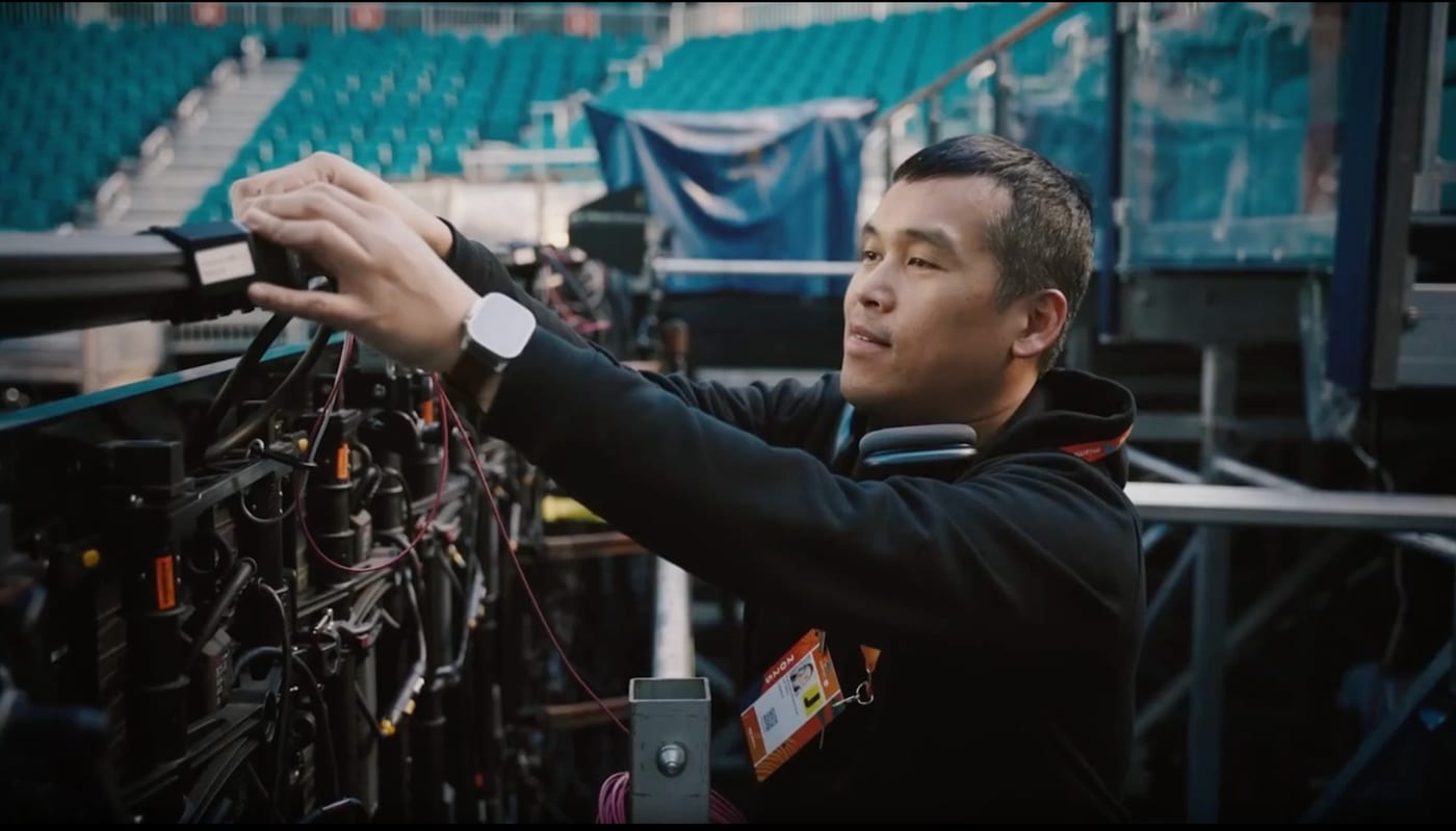 A Muybridge engineer installing a sensor module on a rig in an empty stadium with teal seating at the Miami Open